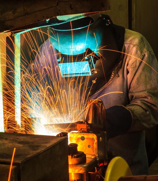 Welder with a safety mask on with sparks flying