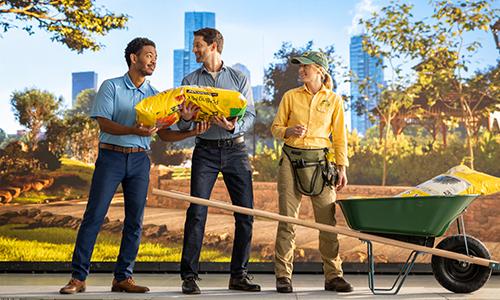 An agent helps a landscaper unload her wheelbarrow by handing a bag of mulch to a Texas Mutual employee. 