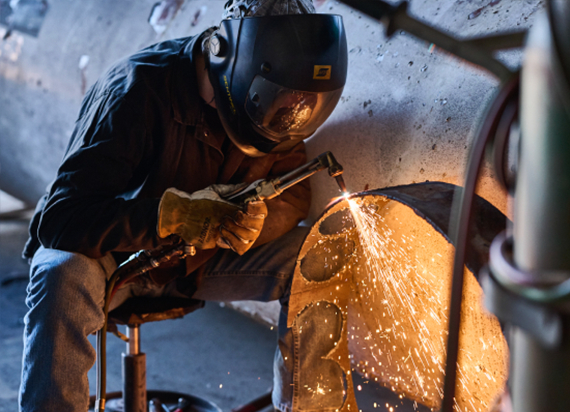 A welder working with safety gear on and making sparks.